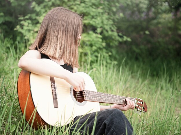 Chica adolescente tocando la guitarra en el parque