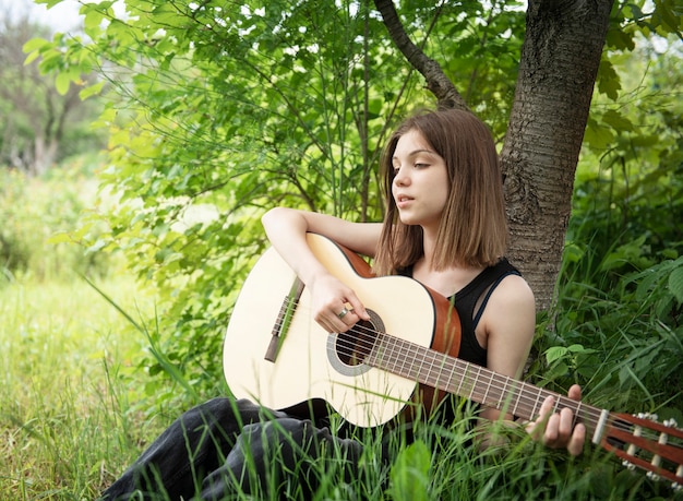 Chica adolescente tocando la guitarra en el parque