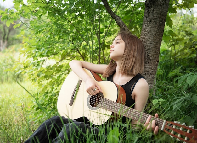 Chica adolescente tocando la guitarra en el parque