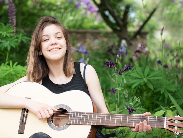 Chica adolescente tocando la guitarra en el parque