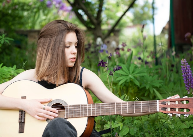 Chica adolescente tocando la guitarra en el parque