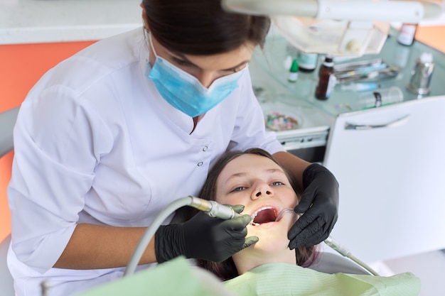 Chica adolescente tratando los dientes en el consultorio del dentista, consulta de ortodoncista. Odontología, dientes sanos, medicina y concepto de salud