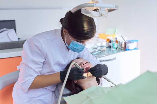 Chica adolescente tratando los dientes en el consultorio del dentista, consulta de ortodoncista