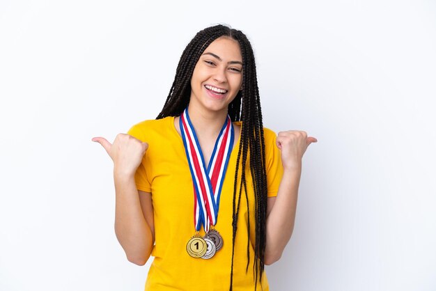 Foto chica adolescente con trenzas y medallas sobre fondo rosa aislado con pulgares arriba gesto y sonriendo