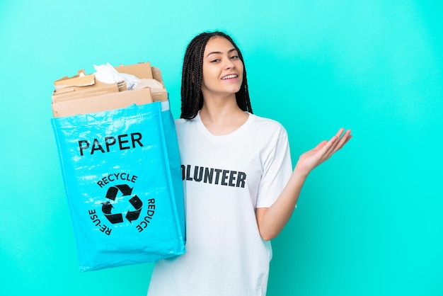 Chica adolescente con trenzas sosteniendo una bolsa para reciclar extendiendo las manos hacia un lado para invitar a venir