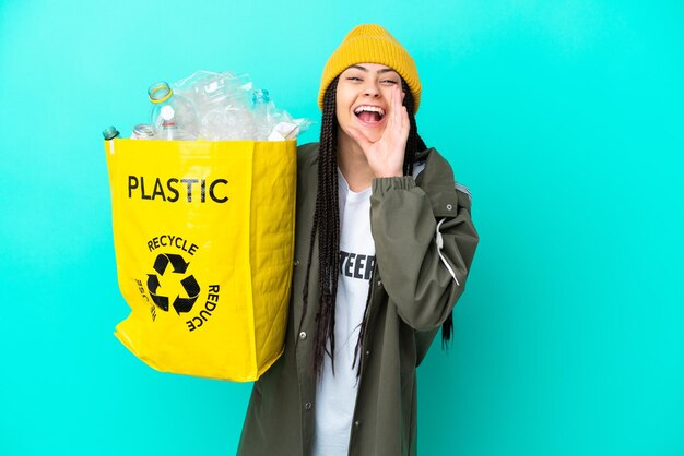 Chica adolescente con trenzas sosteniendo una bolsa para reciclar gritando con la boca abierta