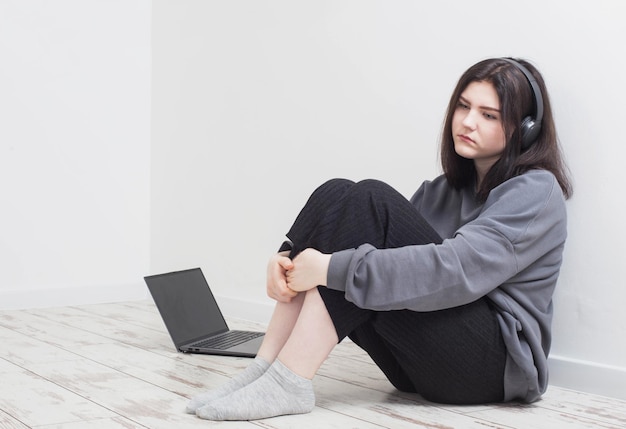 Chica adolescente triste con laptop sentada en el piso