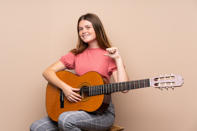 Chica adolescente ucraniana con guitarra aislada orgullosa y satisfecha de sí misma