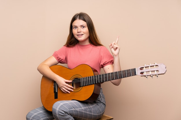 Chica adolescente ucraniana con guitarra apuntando hacia una gran idea