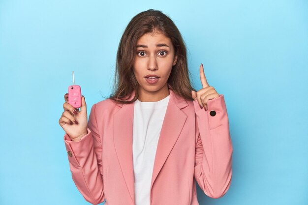 Chica adolescente vestida de rosa sosteniendo con orgullo la llave de su auto teniendo un concepto de inspiración idea