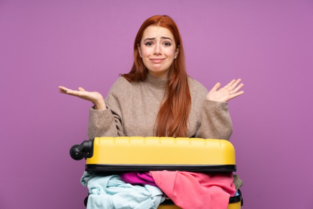 Chica adolescente viajero con una maleta llena de ropa que tiene dudas con expresión de la cara confusa