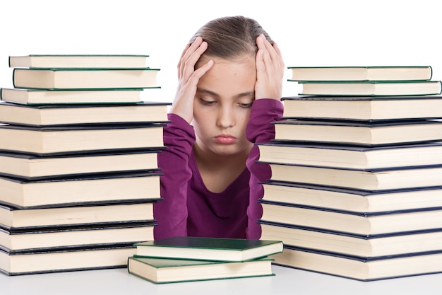 Chica adorable concentrada con muchos libros sobre un fondo blanco