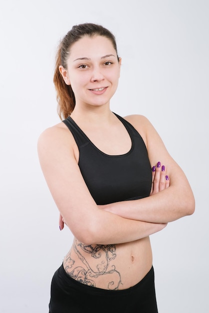 Chica adulta atlética en un traje deportivo haciendo ejercicios sobre un fondo blanco.