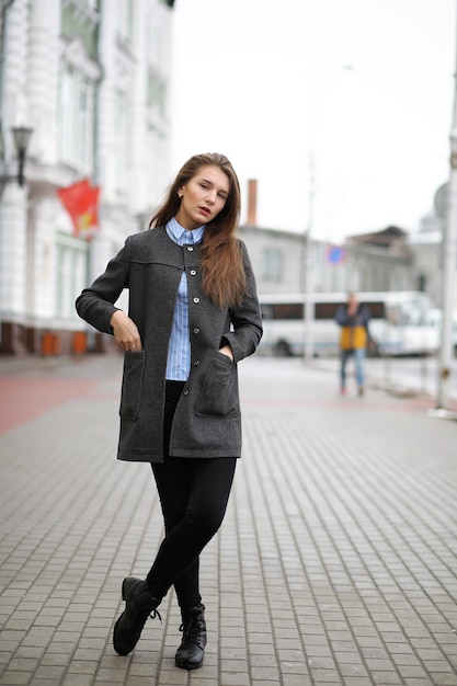 Chica adulta joven en abrigo en la calle de la ciudad
