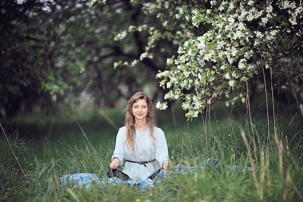 Chica adulta meditando en el exuberante huerto de manzanas Primavera