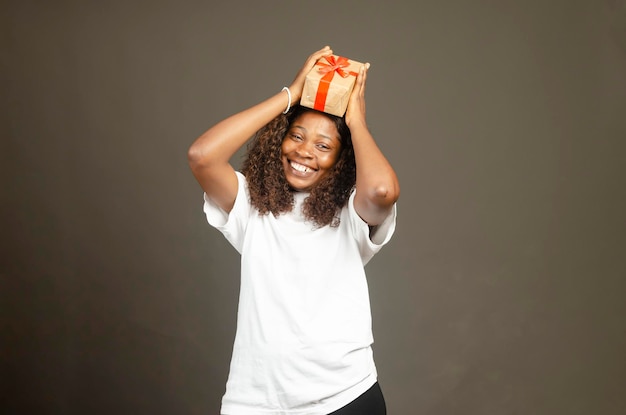 Chica africana emocionada levantando caja de regalo