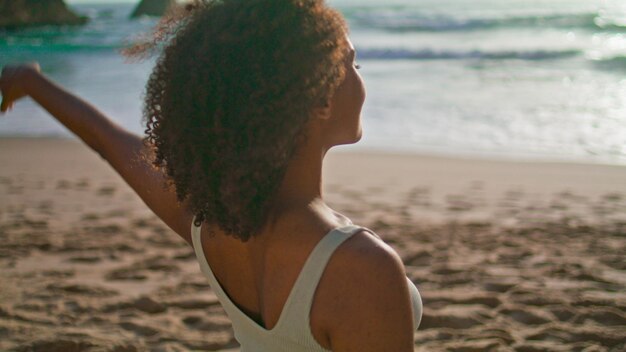 Chica africana estirando el cuello en la playa de arena de cerca