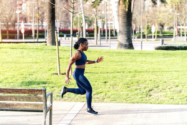 Chica afro negra corriendo en un parque público al atardecer