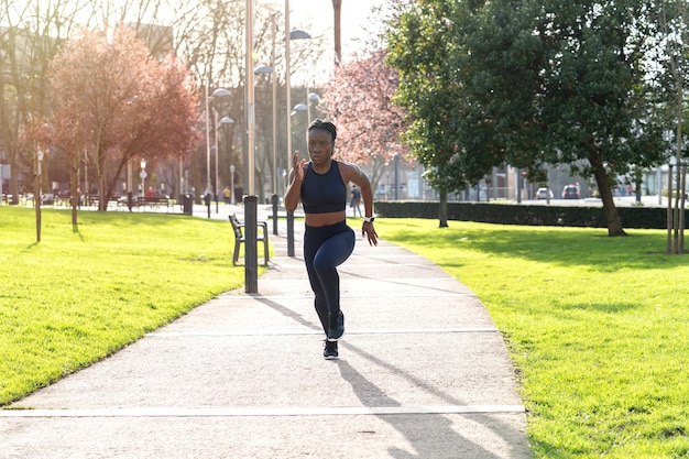 Chica afro negra corriendo en un parque público al atardecer