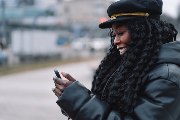 Chica afro usa el teléfono al aire libre.