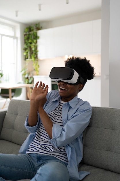 Chica afroamericana asustada con gafas VR en los ojos sonriendo se inclina mirando hacia atrás una película 3D genial