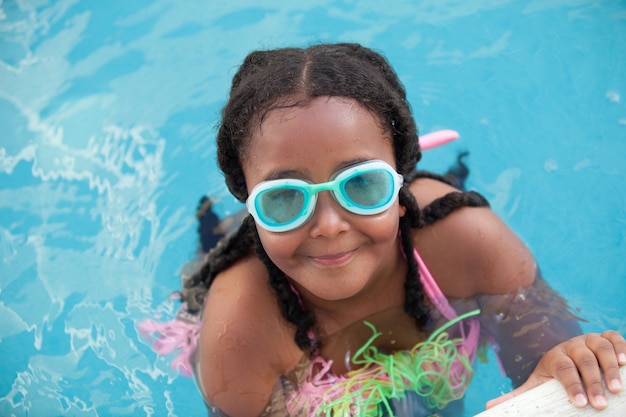 Chica afroamericana divertida con gafas en la piscina