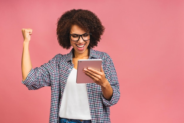 Chica afroamericana feliz mirando emocionada mirando la pantalla de su tableta celebrando la victoria haciendo gesto de ganador gritando y riendo Concepto de alegría de felicidad de éxito