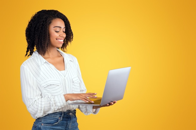 Una chica afroamericana sonriente con una computadora personal