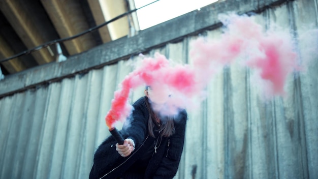 Chica agitando bomba de humo a la cámara Mujer protestando en la calle con bengala de humo