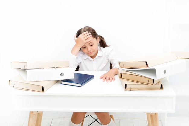 Chica agotada con libro y carpetas. Educación. aburrida lección. Hacia el conocimiento. pequeña niña en la lección. tarea y educación en casa. niño aprende y estudia mucho. De vuelta a la escuela. cansado y somnoliento.