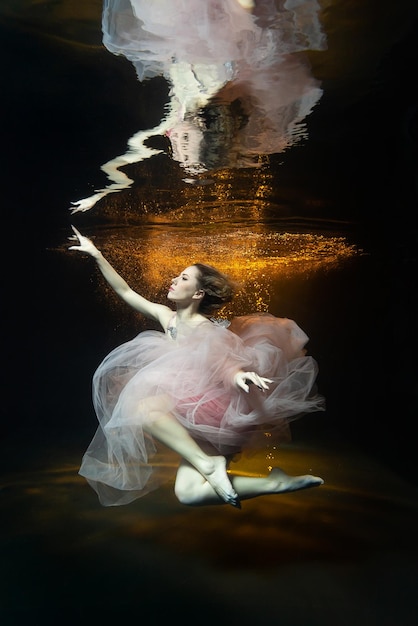 Una chica bajo el agua en la piscina de un estudio fotográfico con un vestido.