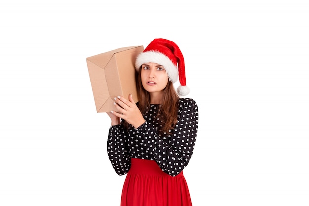 Chica alarmada con su regalo escucha lo que hay en la caja, aislado en blanco