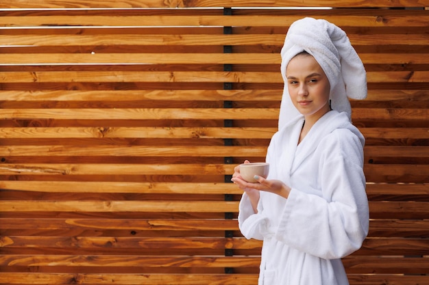 Foto una chica con albornoz y una toalla envuelta en la cabeza disfruta de un té fragante por la mañana