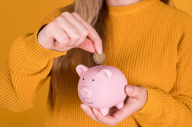 Chica con una alcancía, inserta monedas, para ahorrar, concepto de crisis financiera