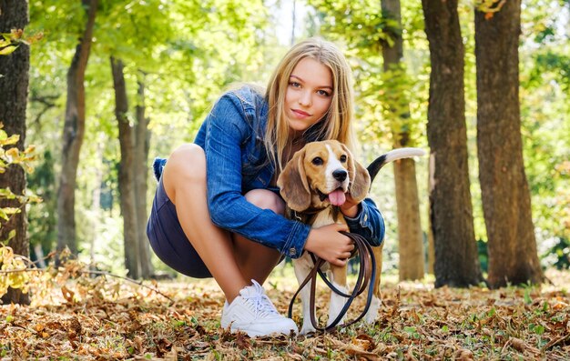 Chica alegre abrazando a un perro en el sol de la mañana