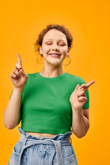 Chica alegre en aretes de camiseta verde posando estilo de moda