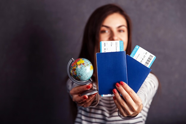 Foto chica alegre con billete de avión de pasaporte y globo terráqueo antes del concepto de viaje interior de fondo gris