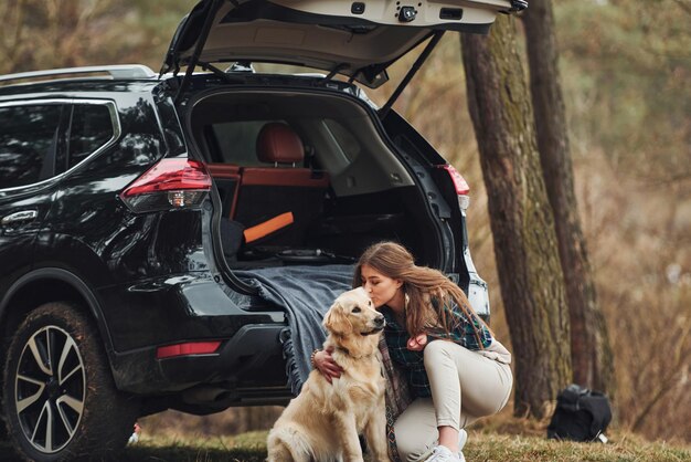 Una chica alegre camina con su perro al aire libre en el bosque en otoño o primavera