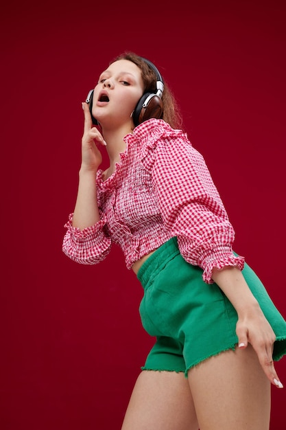 Chica alegre con una camisa rosa escuchando música en los auriculares sin alterar