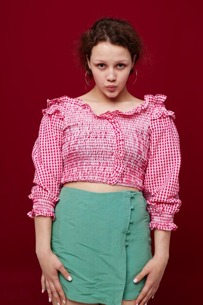 Chica alegre en camisa rosa posando fondo rojo de moda