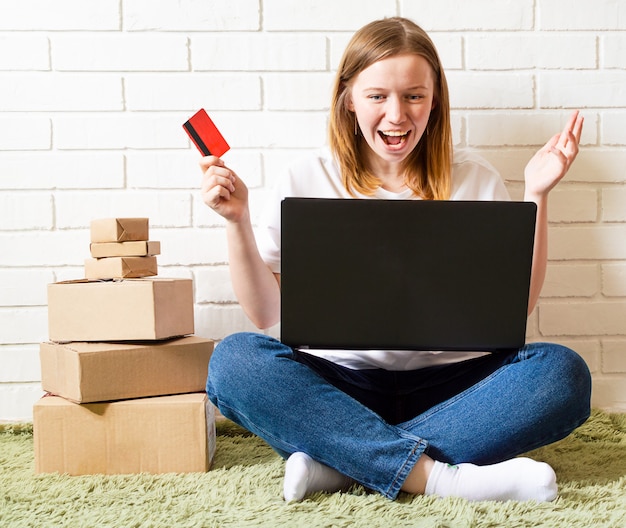 Foto chica alegre compra en línea en la computadora con tarjeta de crédito. pedidos online entrega de compras.