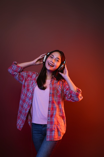 Chica alegre disfrutando de la música con auriculares con dos manos sosteniendo auriculares