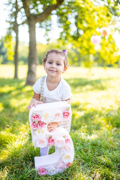 Chica alegre divirtiéndose en el cumpleaños del niño en una manta con adornos de papel en el parque