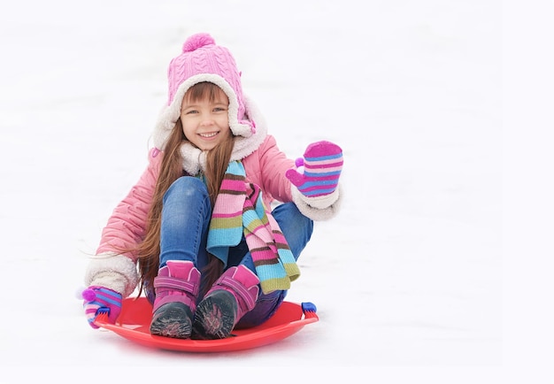 Chica alegre divirtiéndose y trineo sobre la nieve