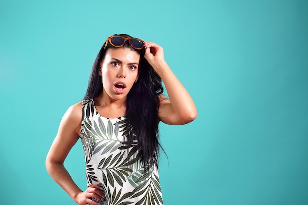 Chica alegre con expresión sorprendida posando sobre un fondo azul en Studio