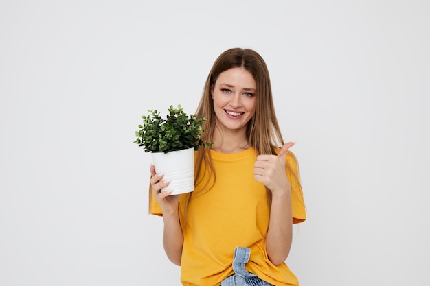 Chica alegre en una flor de camiseta amarilla en una olla posando