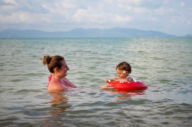 Chica alegre nadando con su mamá en el mar