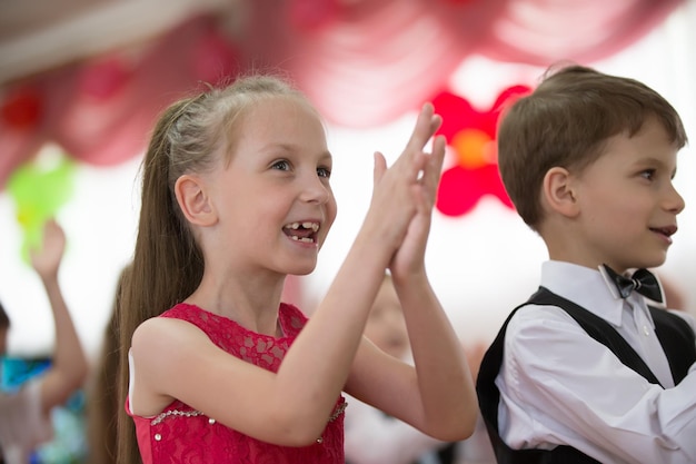 Chica alegre niña preescolar aplaudiendo en una fiesta