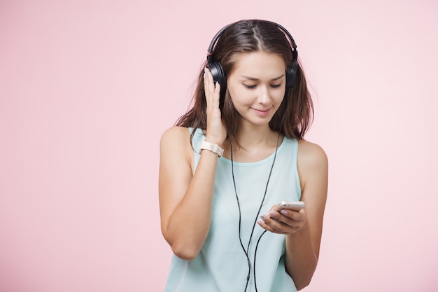 Chica alegre de pelo castaño con auriculares escuchando música