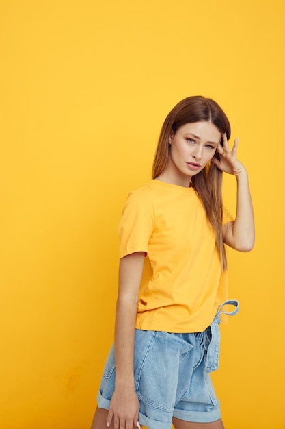 Chica alegre con el pelo largo en pantalones cortos de mezclilla y una camiseta